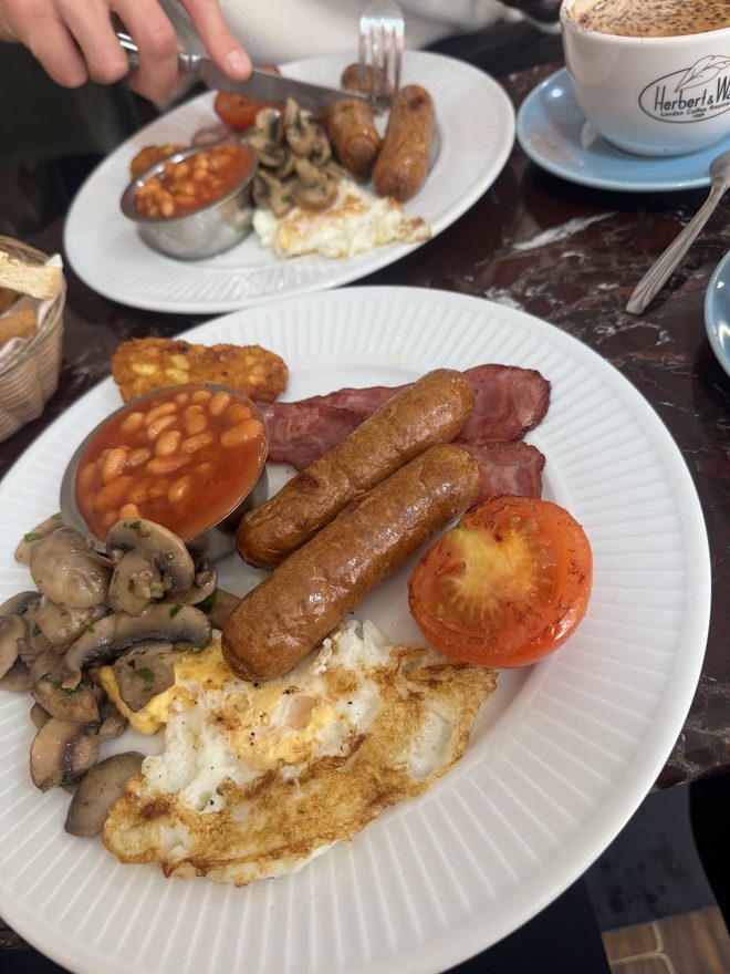 A full English breakfast with a second plate and coffee behind